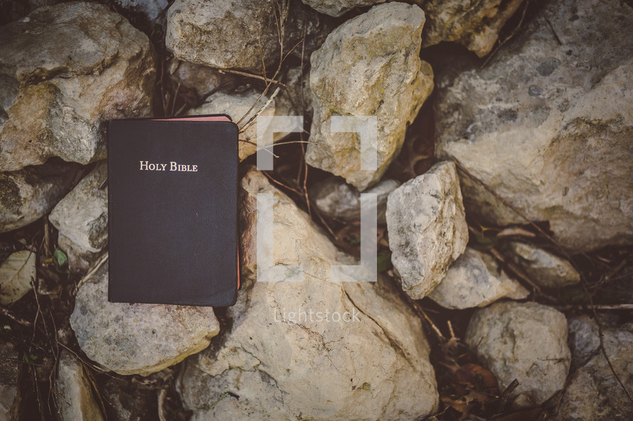 Holy Bible on rocks outside.