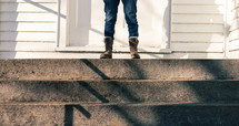 a woman in boots standing on steps in front of a church 