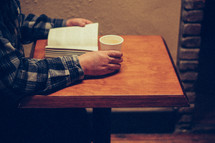 man reading a Bible and coffee mug 