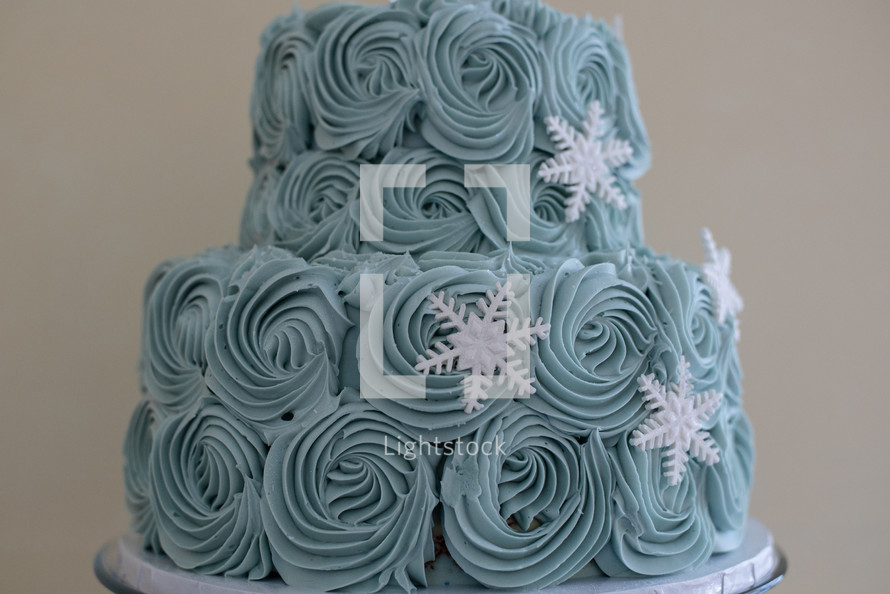 Blue buttercream frosting and sugar snowflakes on a cake