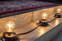 Lightbulbs along a step with a rug on the stage