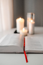 opened Bible spine and candles 