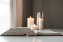 opened Bible spine and candles 