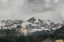 snow capped mountain peaks in the clouds and cabin roof 