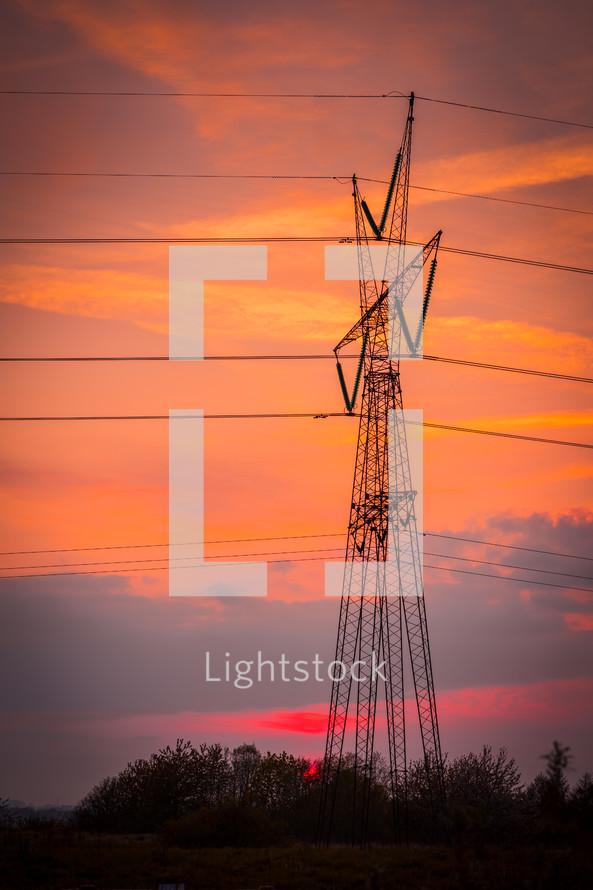 power lines at sunset under an orange sky 