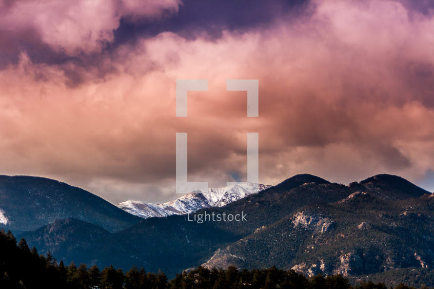 pink clouds over a snow covered mountain peak 