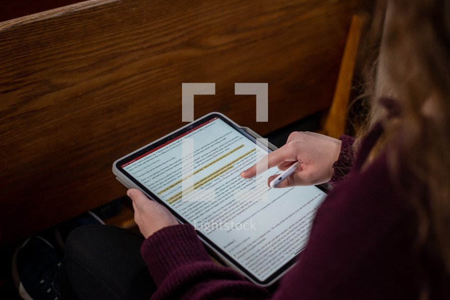 Woman taking notes in her Bible on a tablet