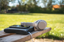 headphones, cellphone, and Bible on a bench 