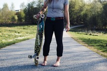 a teen girl standing holding a skateboard 