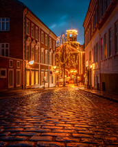 Christmas lights and a cobblestone street at night 