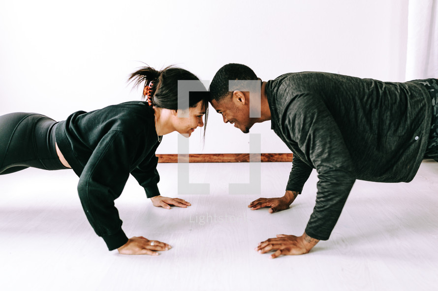 a couple doing push-ups together 