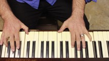 man playing an upright acoustic piano 