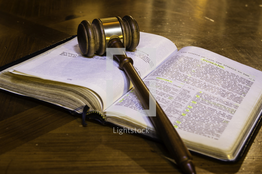  a gavel on a Bible open to Romans