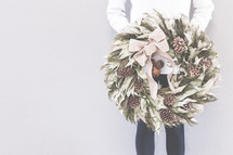 a woman holding a Christmas wreath 