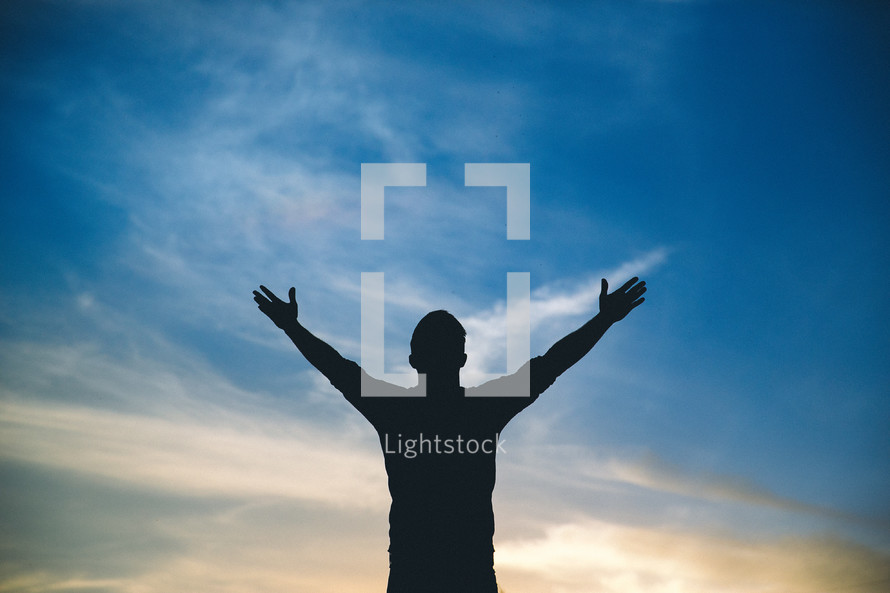 silhouette of a man with raised hands in worship to God 