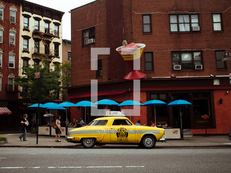 yellow taxi cab in front of a cafe 