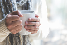 a woman holding a warm mug 