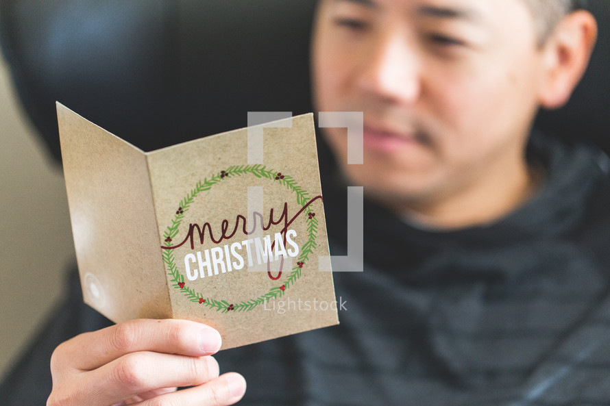 a man reading a Christmas greeting card 