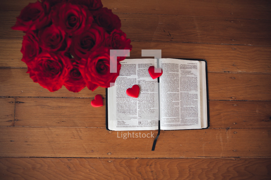 Red roses and candy hearts on the pages of a Bible. 