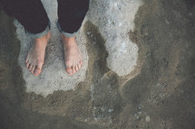 man's  bare feet standing on sand