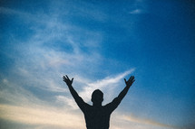 silhouette of a man with raised hands of worship 