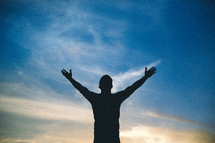 silhouette of a man with raised hands in worship to God 