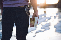 A man standing holding a Bible at his side 