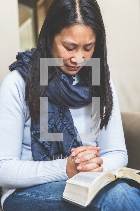 woman praying over a Bible in her lap 