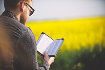 a man reading a Bible outdoors 