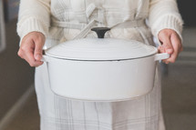 a woman holding a dutch oven 