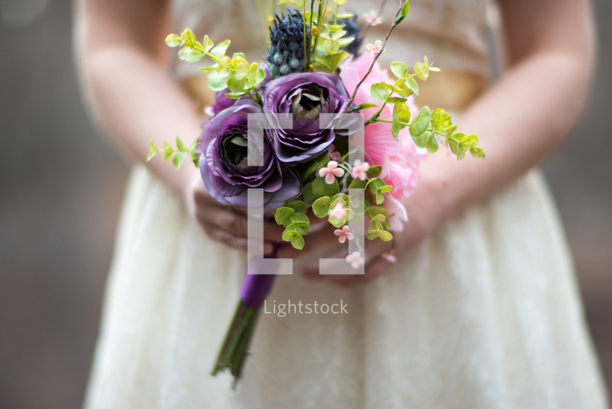 A young woman holding a bouquet of purple flowers.