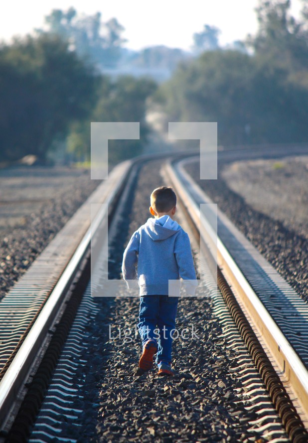 boy child walking alone on train tracks