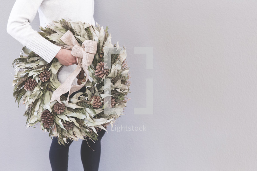 a woman carrying a Christmas wreath  