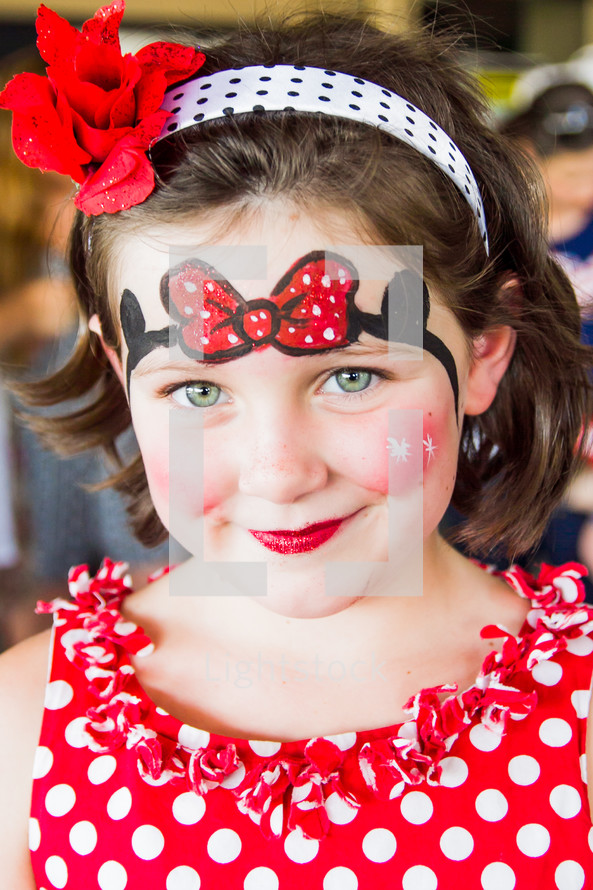 girl child with Minnie Mouse face paint 