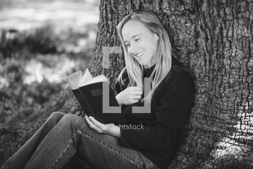 woman reading a Bible under a tree