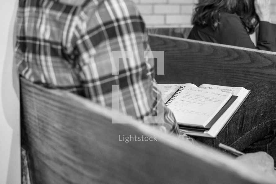 Man writing sermon notes in a pew - black and white
