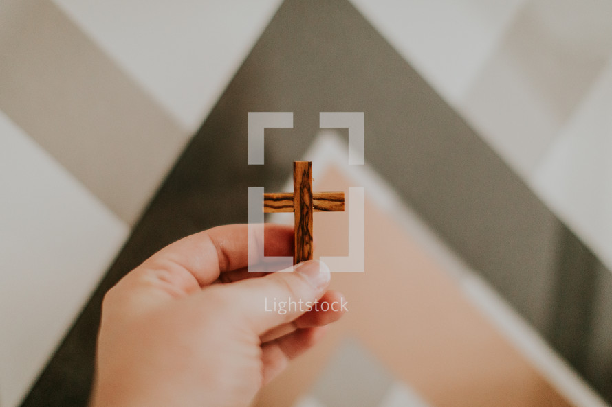 hand holding up a wooden cross