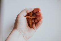 cupped hand holding a wooden cross