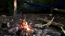 flames in a campfire near a hammock 