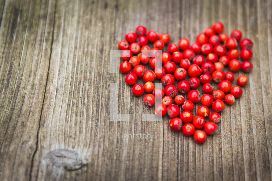 heart of red berries on a wood background 