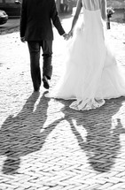 A bride and groom walk away holding hands.