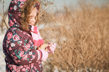 a girl child in a winter coat standing outdoors 