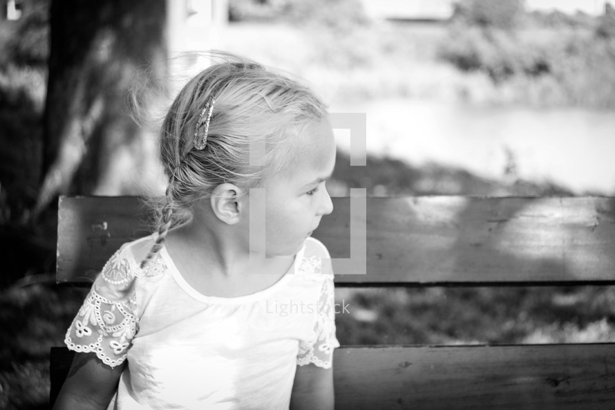 a child with braids sitting on a park bench