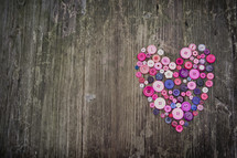 a heart of buttons on a wood background 