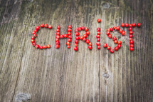 word Christ in red berries on a wood background 