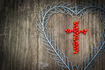 a heart of berries in a a blue metal cross 