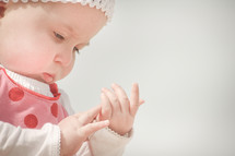 A baby examines her hands.