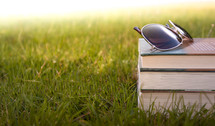 sunglasses on a stack of books in the grass 