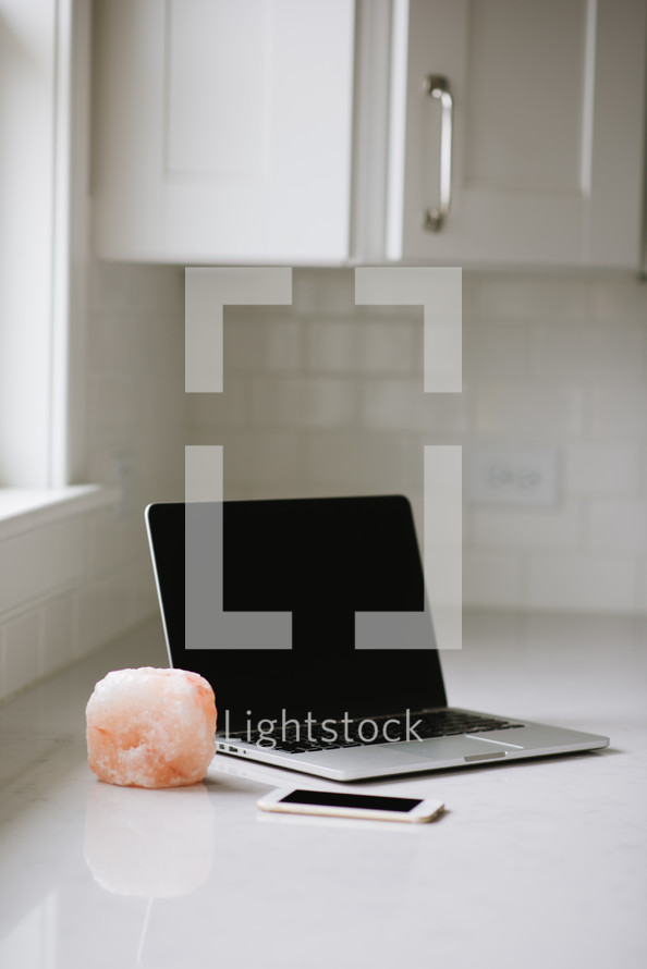 laptop computer, iPhone, and salt lamp candle in a kitchen 