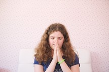 a girl kneeling in prayer beside her bed 
